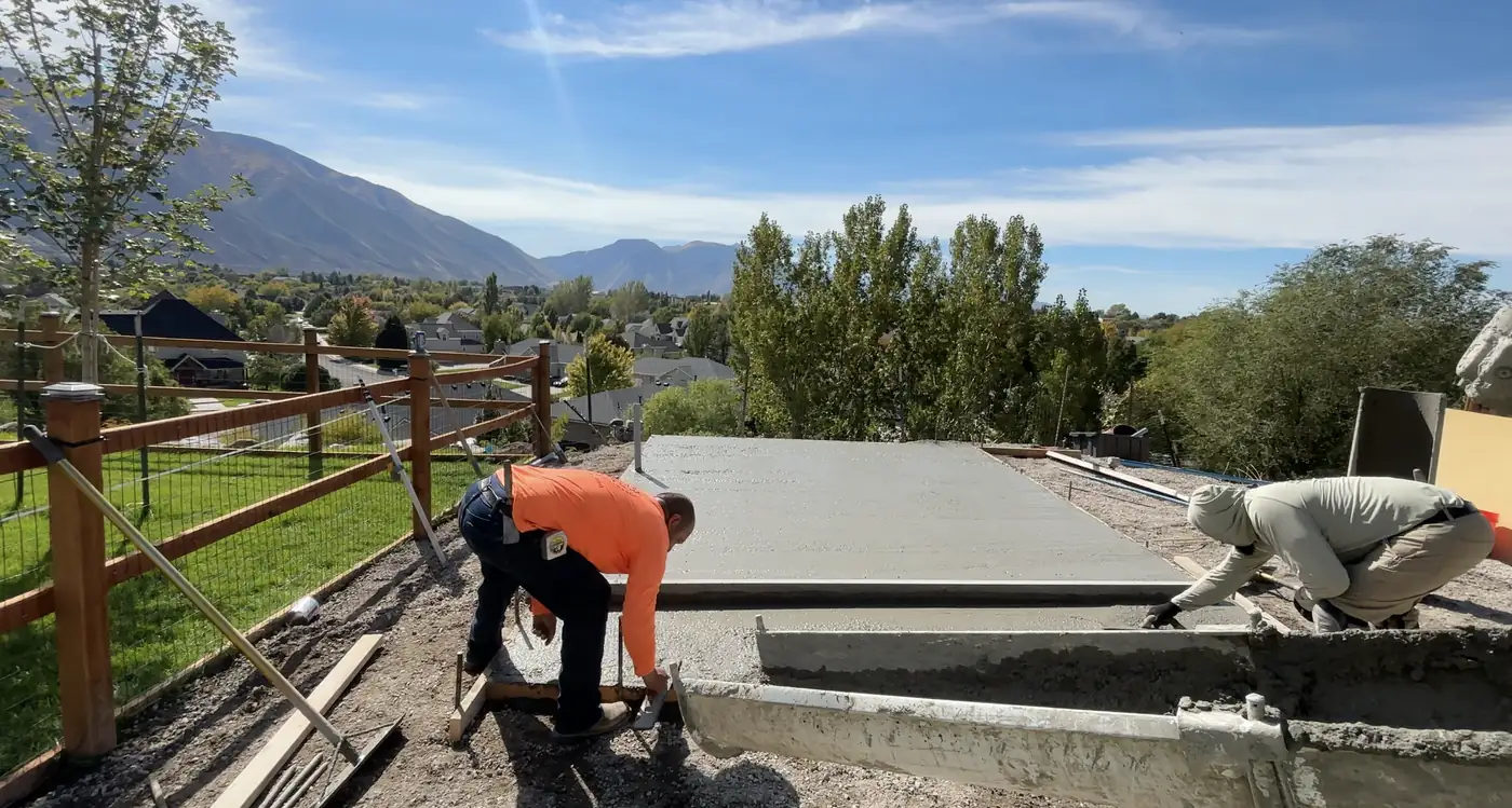 Crew finishing a new concrete pad with mountains behind